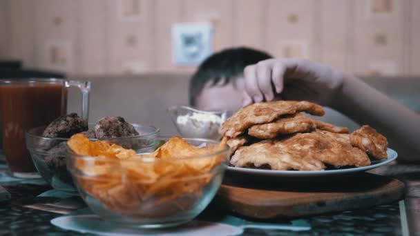 Hambriento chico mano de debajo mesa toma patatas fritas en plato mientras nadie ve — Vídeos de Stock