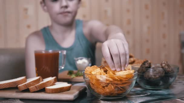 Hambriento niño mano toma crujiente de oro patatas fritas de la placa. Comida chatarra en la cena — Vídeos de Stock