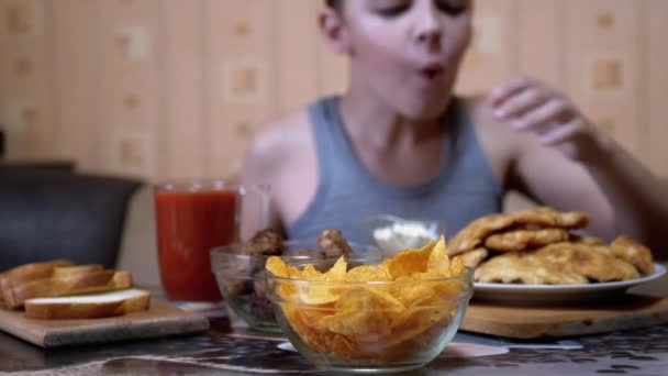 Hambriento niño mano toma crujiente de oro patatas fritas de la placa. Comida chatarra en la cena — Vídeos de Stock