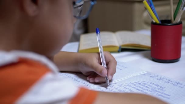 Schoolboy escreve com a mão esquerda no caderno, usando alça. Treinamento doméstico online — Vídeo de Stock