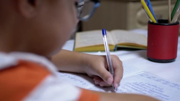 Colegial escribe con la mano izquierda en el cuaderno, usando la manija. Formación en línea en casa — Vídeos de Stock