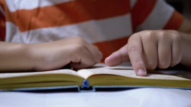 Το παιδί τρέχει δάχτυλο κατά μήκος της σελίδας του βιβλίου και διαβάζει γρήγορα. Ανάγνωση απομακρυσμένα στο σπίτι — Αρχείο Βίντεο