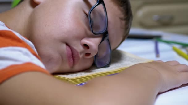 Niño curioso con gafas se quedó dormido en el libro Leer en la mesa. Fatiga, sueño — Vídeo de stock