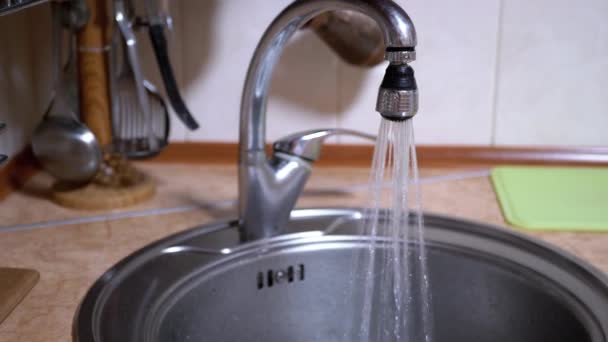 L'acqua di un rubinetto aperto nichelato scorre nel lavandino in una cucina moderna — Video Stock