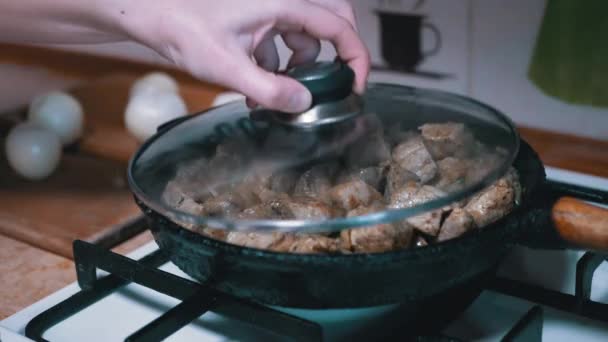 Mão feminina abre tampa e verifica prontidão carne na frigideira. Home Cozinha — Vídeo de Stock