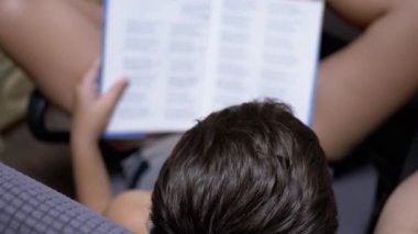 Gözlüklü Ciddi Çocuk, Sandalyeye Oturup Evde İlginç Bir Kitap Okuyor