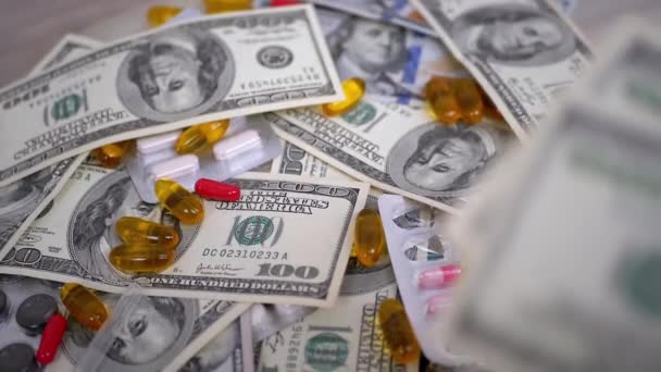 Paquete de billetes de dólar cae en la mesa con dinero, píldoras. Aumento de los costes sanitarios — Vídeo de stock