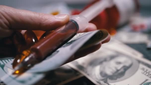Мужчина раздает деньги, доллары на покупку таблеток и шприц для анализа крови — стоковое видео