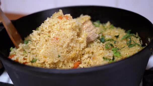 Vrouwelijke hand mengt rijst met groenten, vlees. Oezbeekse Pilaf koken met varkensvlees — Stockvideo