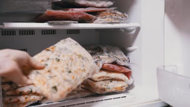 Жіночі руки розкладають заморожені овочеві брикети в морозильній камері. заморожування овочів — стокове відео