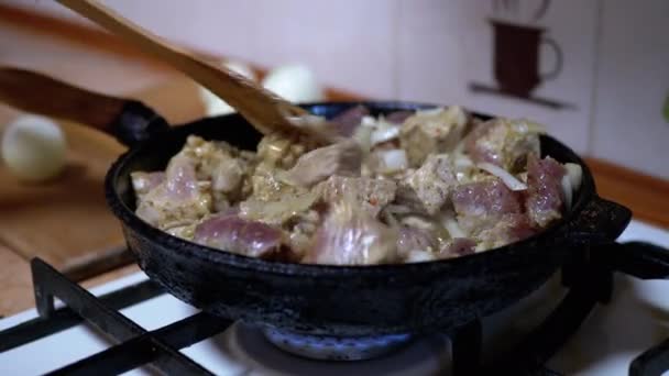 La mano femminile controlla la prontezza della carne fritta con patola di legno. Cucina casalinga — Video Stock