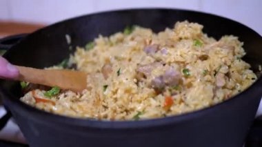 Kadın El, pirinci sebzelerle karıştırıyor, Et. Domuz etiyle Özbek Pilaf Pişirme