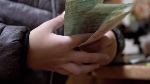 Dítě v bundě drží a počítá bankovky z Hryvnie, peníze v rukách. Detailní záběr — Stock video