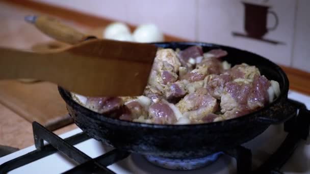 La mano femenina comprueba la preparación de la carne frita con espátula de madera. Cocina casera — Vídeo de stock