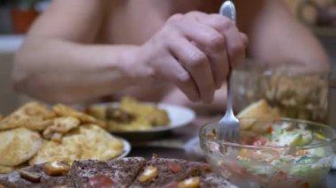 Ev Mutfağı 'nda elinde çatal olan aç adam sebze salatası yiyor. Akşam yemeği