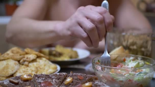 Hladový muž s vidličkou v ruce jí zeleninový salát v domácí kuchyni. Večeře — Stock video