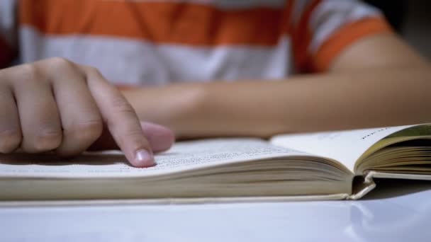 Niño corre dedo a lo largo de la página del libro y lee rápidamente. Lectura remota en casa — Vídeo de stock