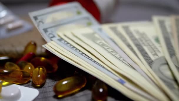 Paquete de billetes de dólar cae en la mesa con dinero, píldoras. Aumento de los costes sanitarios — Vídeos de Stock