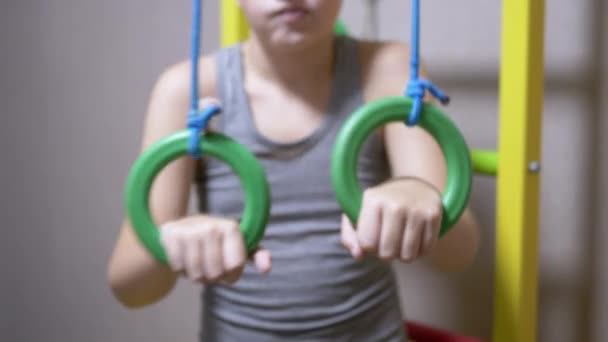 Мальчик делает упражнения на спортивных кольцах, Шведская стена дома в спальне. Крупный план — стоковое видео