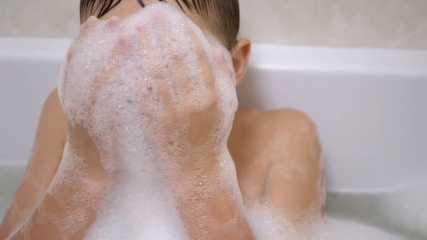 Jongen baden in de badkamer, Spelen met bubbels van zeepachtige schuim, Maakt grappige schuim maskers — Stockvideo