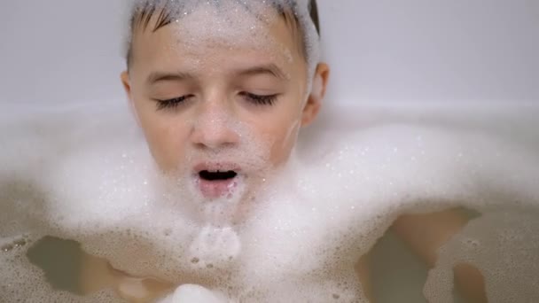 Jongen baden in schuim badkamer, Spelen met bubbels van zeepschuim met schuim in de mond — Stockvideo