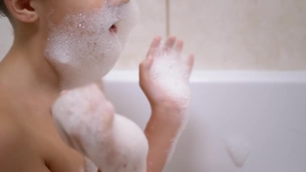 Junge badet im Badezimmer, spielt mit Seifenblasen, macht lustige Schaummasken — Stockvideo