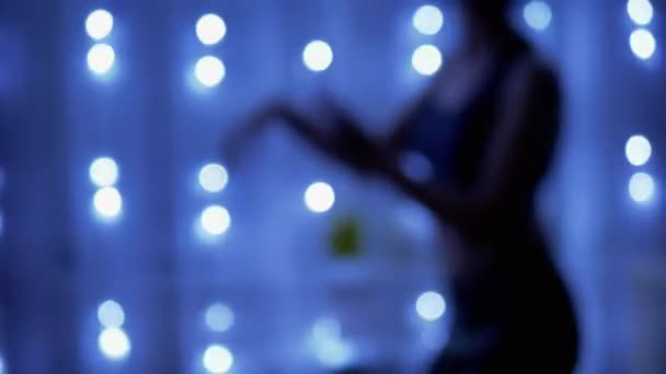 ガーランドライトをフリッカーリングの暗い部屋で踊る女の子のぼやけたシルエット — ストック動画