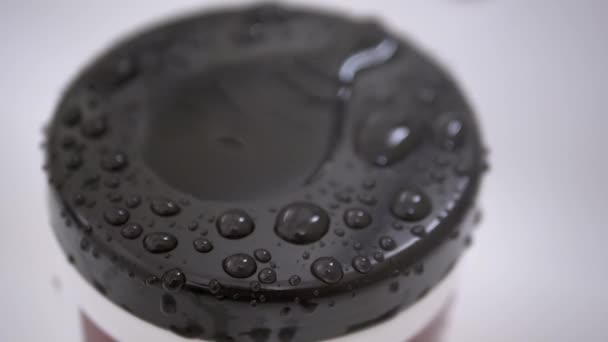 Krople wody Powoli spadać z kranu i rozpylać na czarnej powierzchni plastikowej okładki — Wideo stockowe