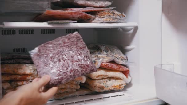 여자 손이 얼어붙은 채소로 만든 브리 켓을 프리저에서 꺼내 주는 모습. 야채를 냉동시키는 일 — 비디오