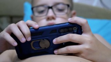 Gözlüklü Ciddi Çocuk, Rahat Yatakta Smartphone 'da Cep Telefonu Oynuyor