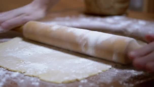 Le mani femminili stendono la pasta sul tavolo di legno con il perno di rotolamento in cucina domestica — Video Stock