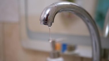 Su damlaları yavaşça aşağı akar, Musluktan lavaboya düşer. Sızıntı.