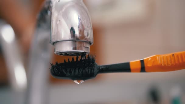 Капли воды из крана медленно падают на зубную щетку Black Bristles. Закрытие — стоковое видео