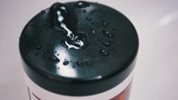 Gotas de agua caen lentamente del grifo y pulverizan sobre la superficie negra de la cubierta de plástico — Vídeos de Stock