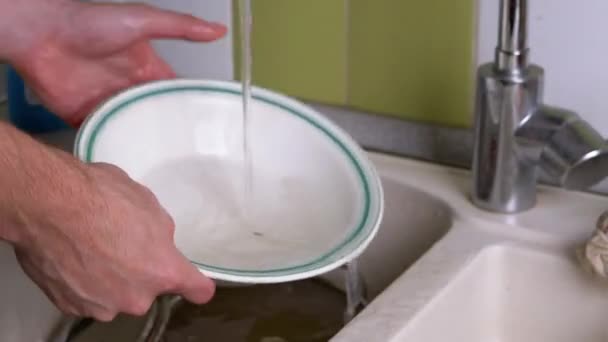 Le mani maschili lavano il piatto sporco nel lavandino della cucina sotto l'acqua corrente. Risciacquo — Video Stock