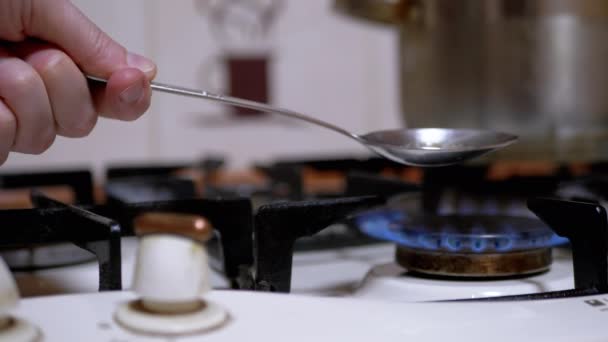 Мужчина-наркоман готовит героин в ложке за газовой плитой дома — стоковое видео