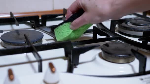 Kvinna Hand en våtservetter och renar, tvättar gas spis, brännare med en grön svamp — Stockvideo