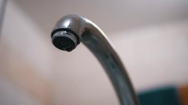 Su damlaları yavaşça aşağı akar, Musluktan lavaboya düşer. Sızıntı.