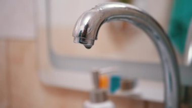 Su damlaları yavaşça aşağı akar, Musluktan lavaboya düşer. Sızıntı.