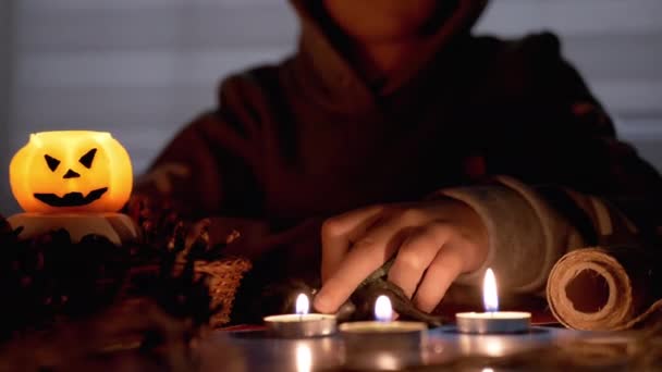 Záhadné dítě uvnitř kapuce hraje s pavoukem od svíčky v tmavém pokoji na Halloween — Stock video