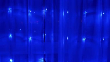 Bir sürü yanıp sönen, yanıp sönen mavi ışıklı perdenin Noel çelengi. 4K