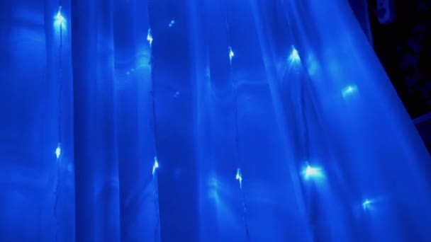 Karácsonyi Garland of Many Blinking, Flickering Blue LED Lights on Curtain. — Stock videók