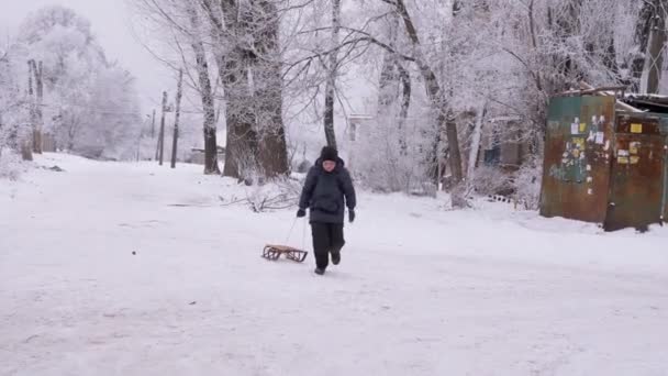 Glimlachende jongen met Sled Runs Up Snowy Road. Roodwangkind. IJzig weer. 4K — Stockvideo