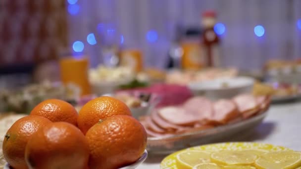 Tangerines op feestelijke kersttafel. Wazige achtergrond met Garland. 4K — Stockvideo