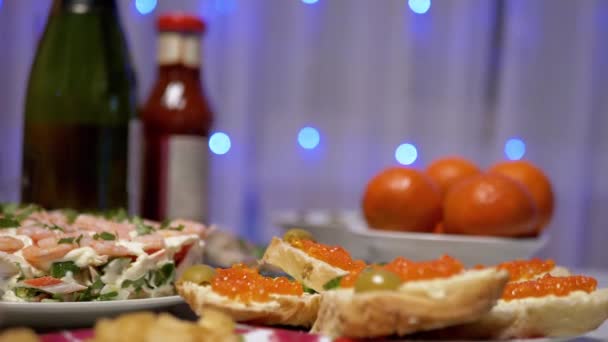 Feestelijke gerechten op tafel rode kaviaar, garnalensalade, mandarijnen, champagne, slinger — Stockvideo