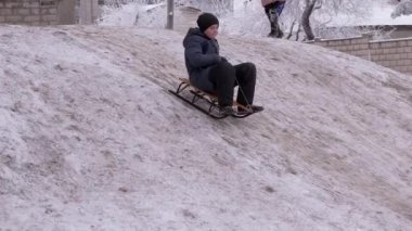 Kış mevsiminde White Hill 'de kızakla kayan mutlu çocuk. Büyüt