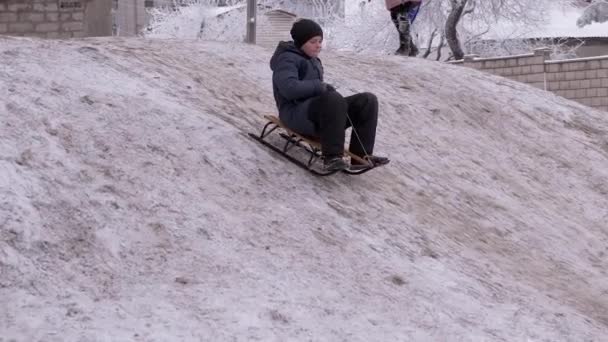 Happy Boy Sledding Down White Hill om vinteren i Yard. Forstør – Stock-video