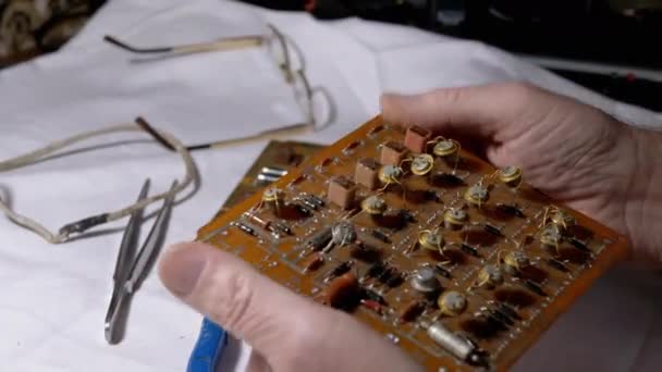 Radiotechnicus onderzoekt kostbare radiotransistors, op een Elektronische Raad. 4K — Stockvideo