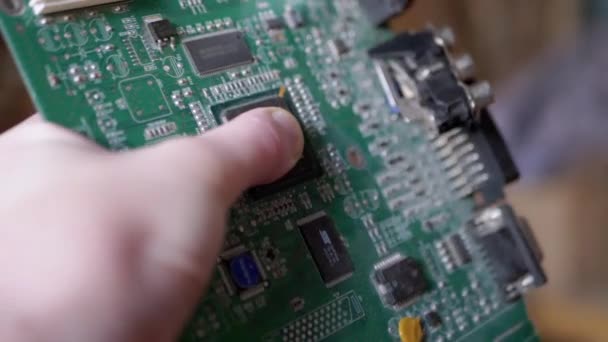 Mão feminina gira placa de circuito impresso antigo com chip, com faixas condutoras — Vídeo de Stock