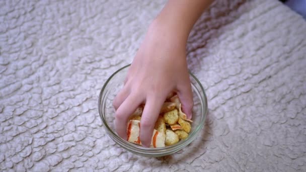 Kid Hand nimmt Chips von einem Teller in der heimischen Küche. Es gibt Fast Food — Stockvideo